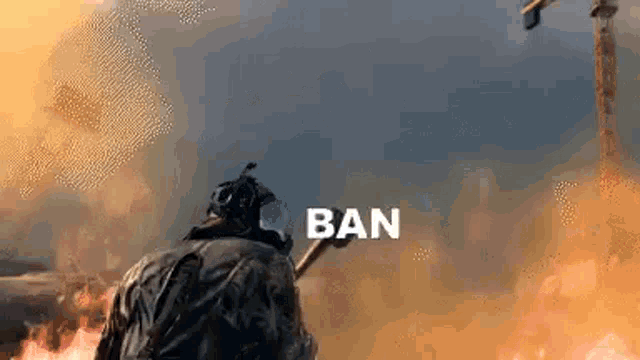 a man in a gas mask is holding a stick in front of a fire and smoke .