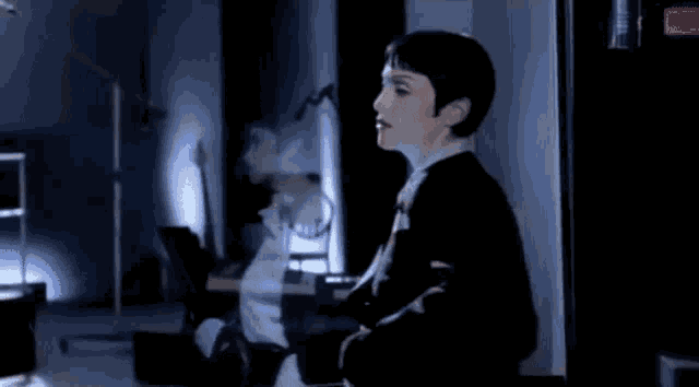 a woman in a suit is standing in a dark room .