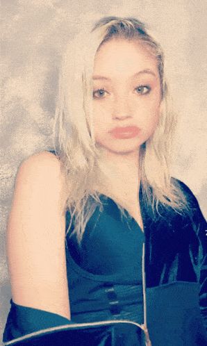 a woman with blonde hair is wearing a blue top and black jacket