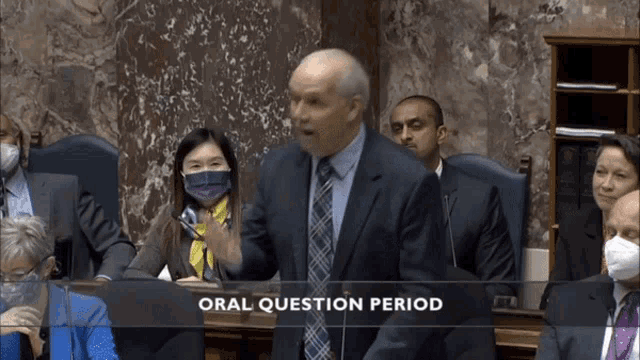 a man in a suit and tie is speaking in front of a group of people and the words oral question period are above him