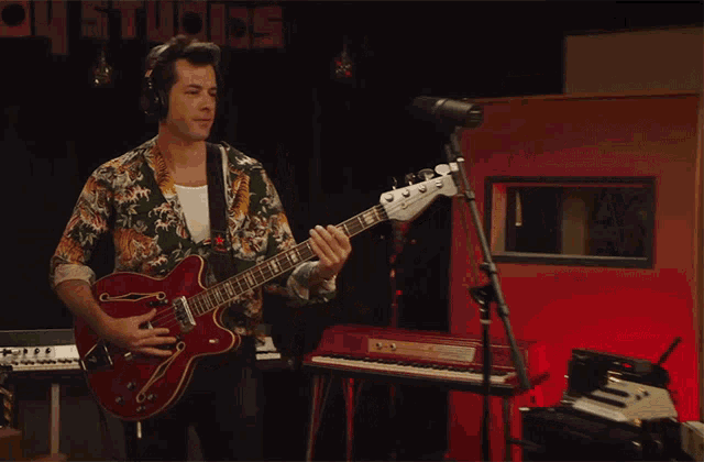 a man in a hawaiian shirt plays a bass guitar