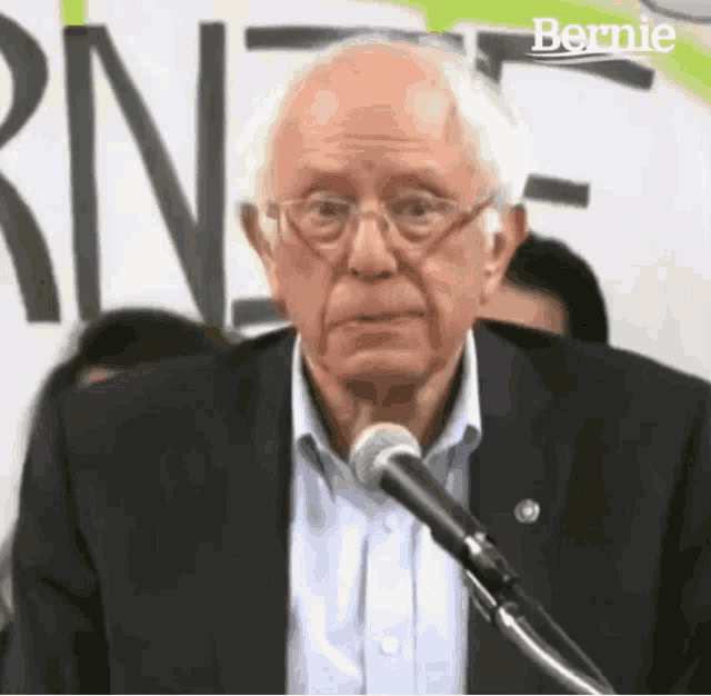 a man in a suit is speaking into a microphone with the word bernie on the bottom