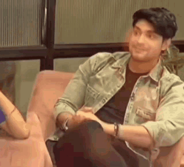 a man is sitting on a couch with his legs crossed and a woman is sitting next to him .