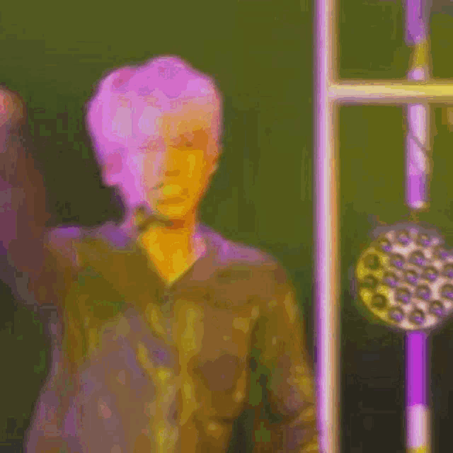 a man in a purple shirt is standing in front of a microphone