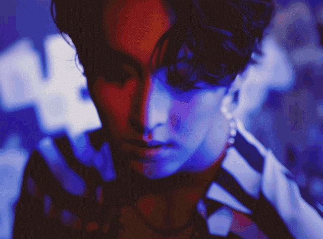 a close up of a person 's face with red and blue lights behind it