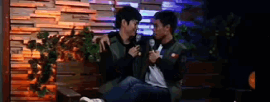 a couple of men are sitting next to each other on a couch .