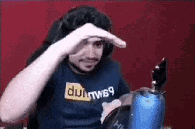 a man wearing a pornhub shirt is sitting at a table with his hand on his forehead .