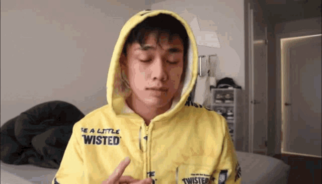 a man wearing a yellow hoodie that says " be a little twisted "