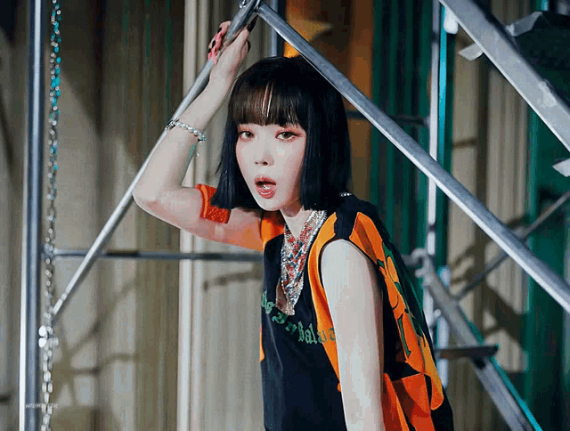 a woman wearing a black and orange tank top with the word adidas on the front