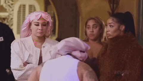 a group of women are standing around a man wearing a white shirt and a pink head scarf .