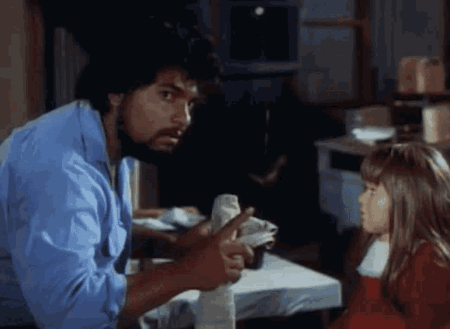 a man with a beard talks to a little girl