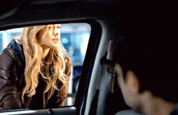 a man and a woman are sitting in a car looking at each other .