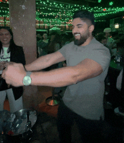 a man in a grey shirt is dancing in a crowded room