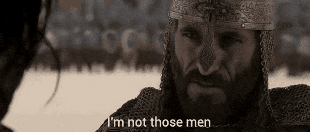 a man with a beard is wearing chain mail and a helmet and says i 'm not those men .
