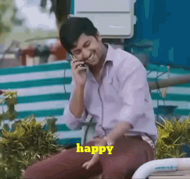 a man is sitting on a bench talking on a cell phone with the word happy in yellow .