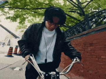 a man wearing headphones is riding a bicycle on a sidewalk