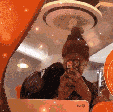 a woman is taking a picture of herself in a mirror with an lg phone in the foreground