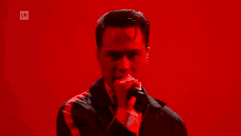 a man in a tuxedo is singing into a microphone on a stage .