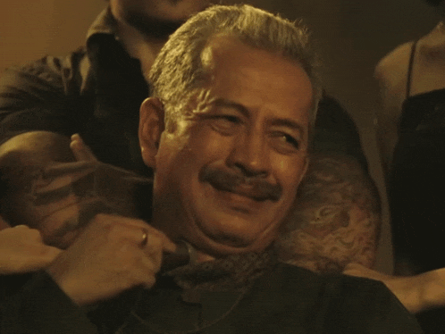 a man with a mustache is smiling while being held by a woman