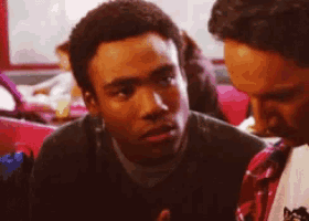 a man in a black sweater is talking to another man in a red plaid shirt