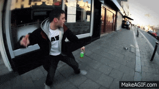 a man wearing a t-shirt that says ' at ' on it is standing on a sidewalk