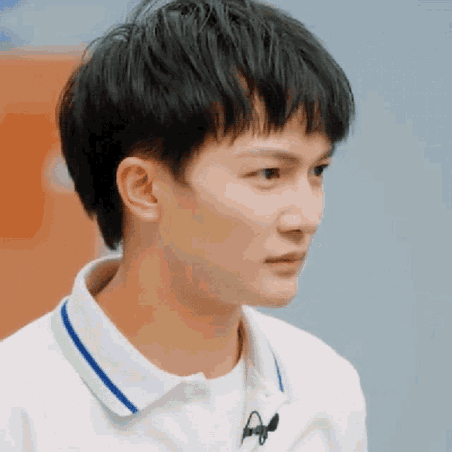 a close up of a young man wearing a white polo shirt