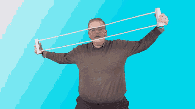 a man in a grey sweater is holding a pair of rubber bands