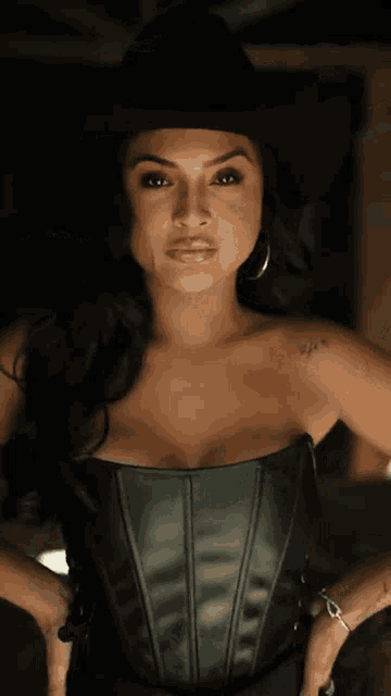a woman wearing a cowboy hat and a corset has a tattoo on her shoulder