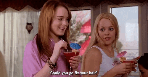 two girls are drinking cocktails and talking to each other while holding drinks .