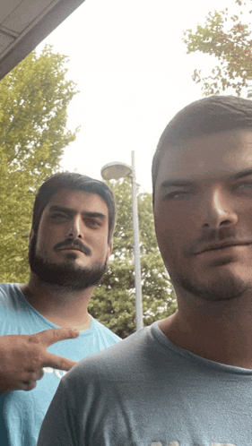 two men are posing for a picture and one is pointing at the camera