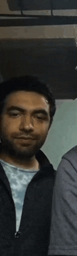 a man with his eyes closed is standing next to another man .