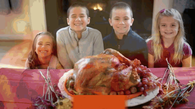 four children are sitting at a table with a turkey and grapes