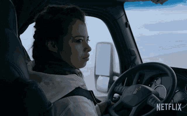 a woman is sitting in the driver 's seat of a netflix truck