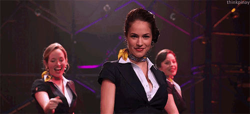 a group of women are dancing on a stage and one of them has her hands on her chest ..