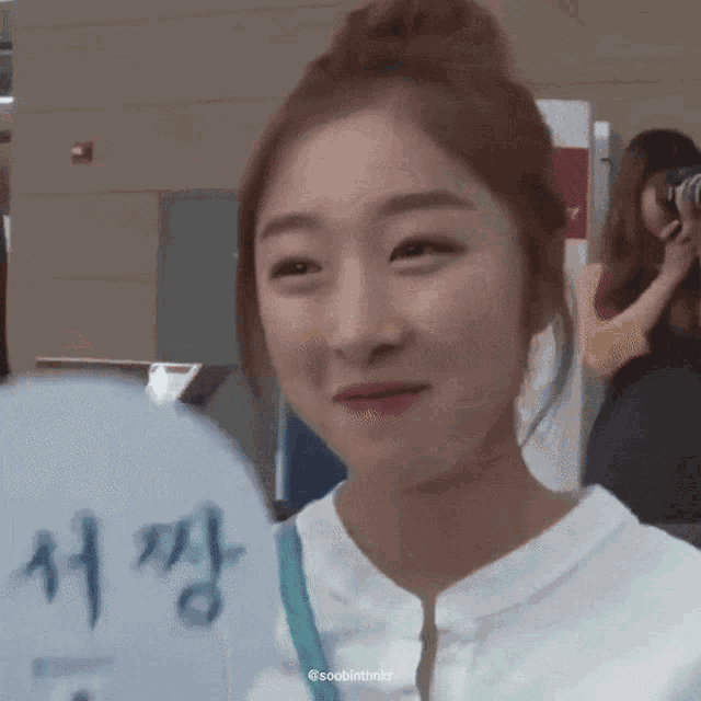 a woman is smiling and holding a fan with chinese writing on it