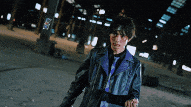a man in a black leather jacket and purple tie is holding someone 's hand