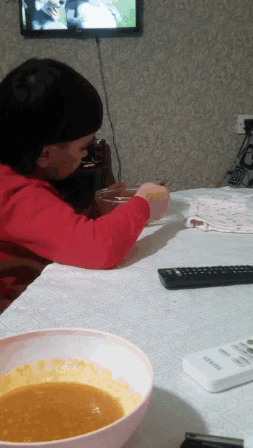 a bowl of soup sits on a table next to a remote