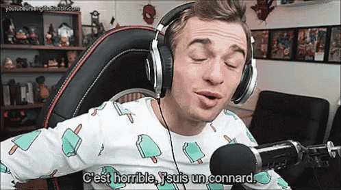 a man wearing headphones is sitting in front of a microphone and talking into it .