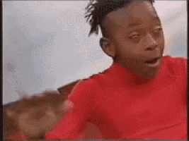 a young boy wearing a red shirt is making a funny face .