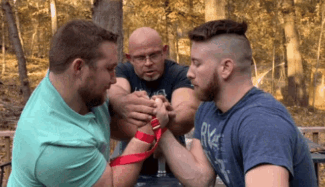two men arm wrestling with one wearing a shirt that says rkc on it