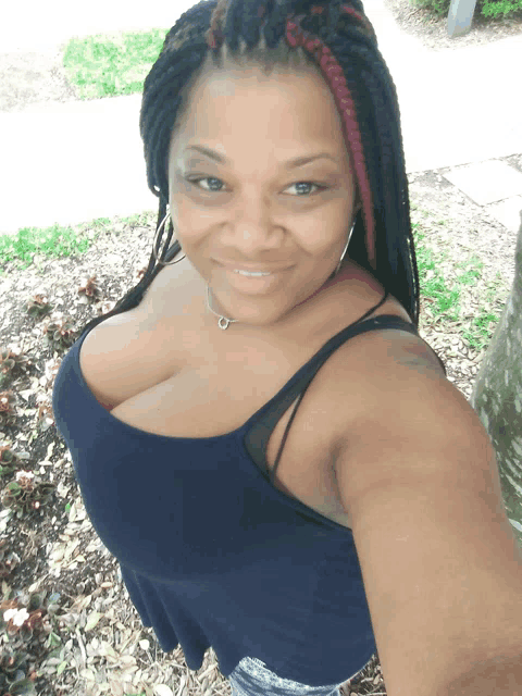 a woman with braids is smiling and wearing a blue tank top and shorts