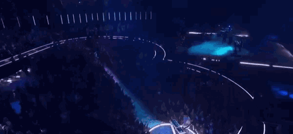 an aerial view of a crowd of people watching a concert in a dark stadium .