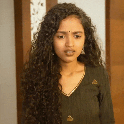 a woman with curly hair is wearing a black top