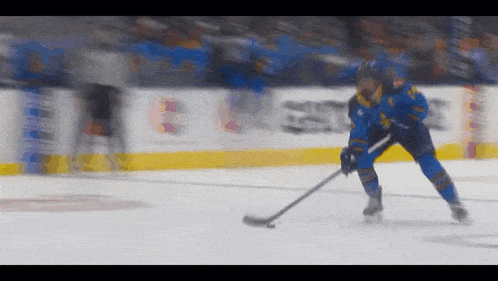 a hockey player in a blue uniform is holding a hockey stick