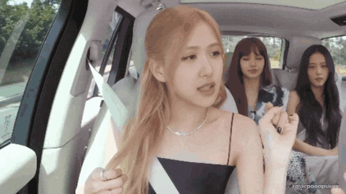 a group of women are sitting in a car and one of them is wearing a necklace and a ring