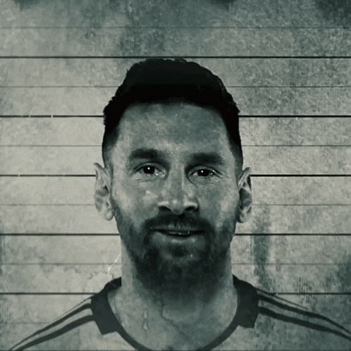 a black and white photo of a man with a beard in front of a wooden wall