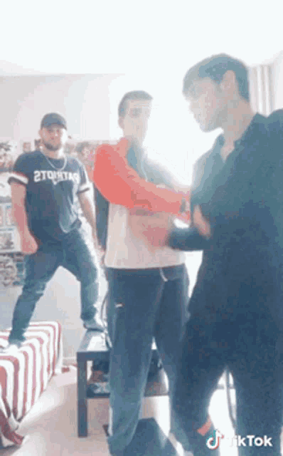 a man wearing a shirt that says 2tqstar is dancing with two other men