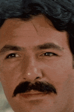 a close up of a man with a mustache making a funny face