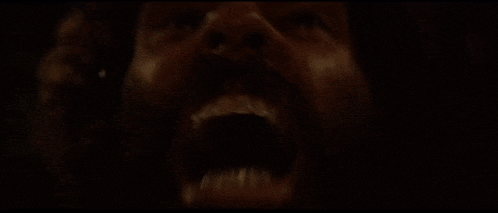 a close up of a man 's face with his mouth open in the dark .