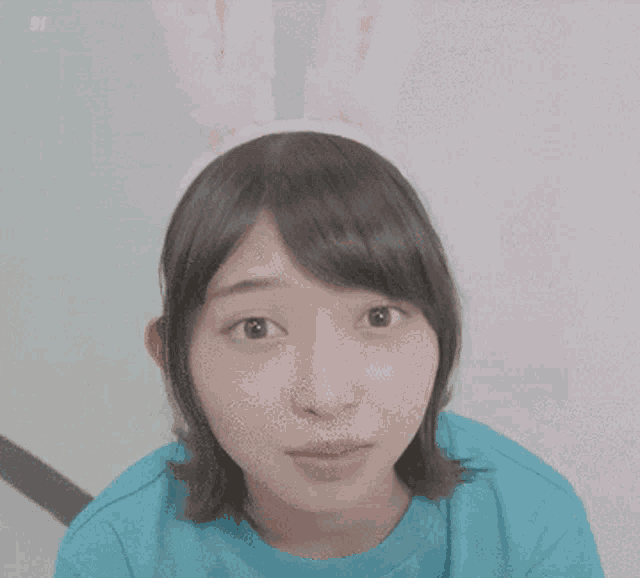 a woman wearing a blue shirt and a cat ear headband